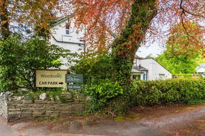 a sign in front of a building next to a tree at Woodside B & B in Keswick