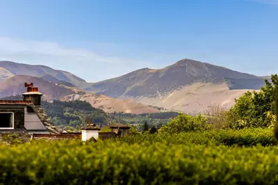 an old house in a field with mountains in the background at Woodside B & B in Keswick