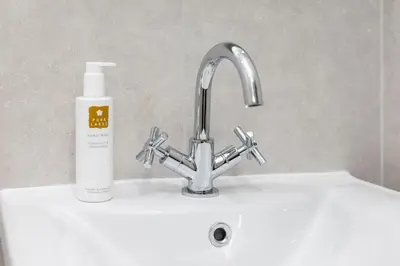 a sink with a faucet and a bottle of soap at Woodside B & B in Keswick