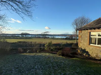 a stone house with a view of a field at Skinnel Cottage in Kirkcudbright
