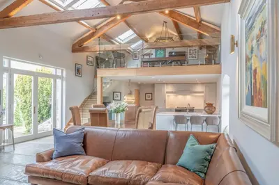 a living room with a brown couch and a kitchen at Luxurious Barn within easy reach of South Lakes! in Boot