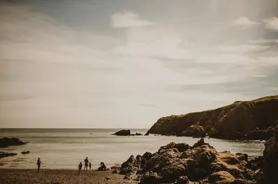 a group of people standing on a beach near the ocean at Castle Penthouse on Estate by the Sea in Enoch