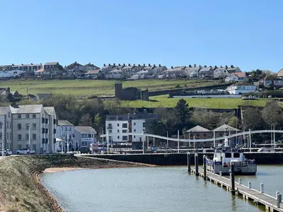 a boat is docked at a dock on a river at Bright 1 Bed Harbour-side Apartment in Whitehaven in Whitehaven