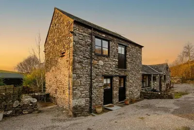 an old stone house in the middle of a yard at Stables Cottage - Wythop Mill in Embleton
