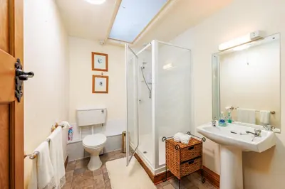a bathroom with a shower and a toilet and a sink at Stables Cottage - Wythop Mill in Embleton