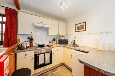 a kitchen with white cabinets and a stove top oven at Stables Cottage - Wythop Mill in Embleton