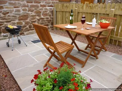a wooden table and chair sitting on a patio at Fortress, Irthington on Hadrians Wall in Irthington