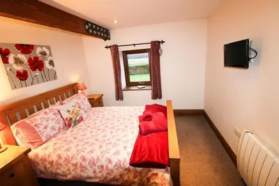 a bedroom with a bed with a red blanket on it at Milecastle, Irthington on Hadrians Wall in Irthington
