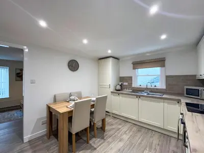 a kitchen and dining room with a wooden table and chairs at Taigh-Beag - Uk50660 in Wigtown
