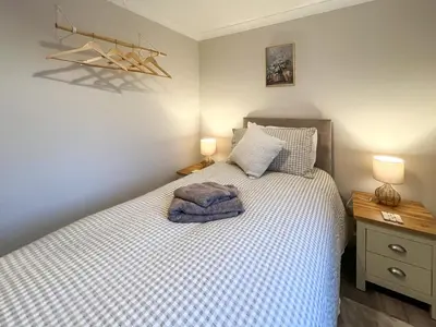 a bedroom with a bed with a blue blanket on it at Taigh-Beag - Uk50660 in Wigtown