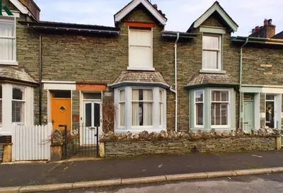 a brick house with an orange door on a street at Wordsworth Cottage in Keswick