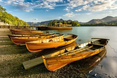 a row of wooden boats sitting on the shore of a lake at Wordsworth Cottage in Keswick