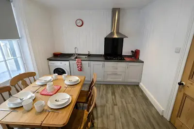 a kitchen with a wooden table with chairs and a stove at Riverside Heights- Dog Friendly Lakeland Retreat in Town Centre in Cockermouth