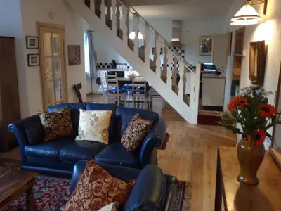 a living room with a blue couch and a staircase at Cargenbank Farmhouse in Lochfoot