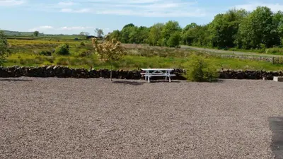 a white picnic table sitting in a gravel field at Cargenbank Farmhouse in Lochfoot