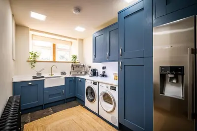 a kitchen with blue cabinets and a washer and dryer at The Old Vicarage Irton in Parton