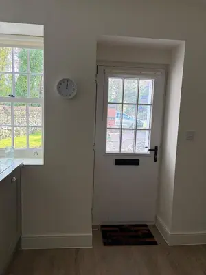 a room with a door and a clock on the wall at Bee Cottage in Moffat