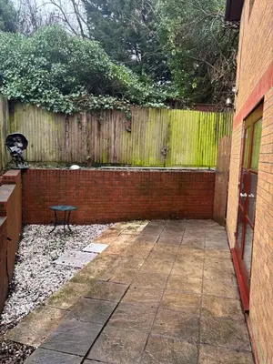 a backyard with a brick fence and a bench at Peace Haven Hendon London NW4 in Moffat