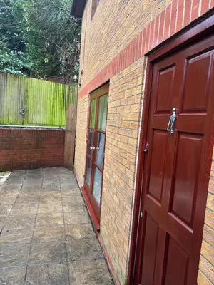 a brick building with a red door and a fence at Peace Haven Hendon London NW4 in Moffat