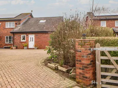 a brick house with a gate and a brick driveway at The Nook in Wigton