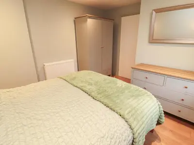 a bedroom with a bed and a dresser and a mirror at The Nook in Wigton