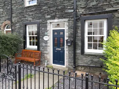 a wooden bench in front of a stone building with a blue door at 22 Rose Terrace in Keswick