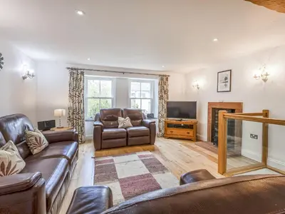 a living room with leather couches and a television at Mary's Cottage in Keswick