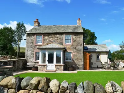 an old stone house with a garden in front of it at Crofthead in Hesket Newmarket