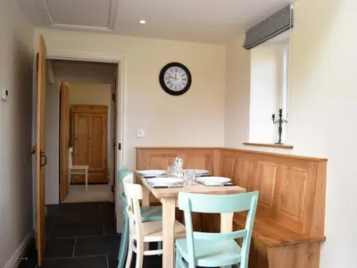 a dining room with a table and chairs and a clock at Crofthead in Hesket Newmarket