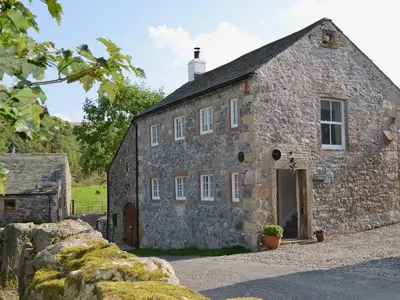 an old stone house with a stone wall at Branthwaite Stable in Caldbeck