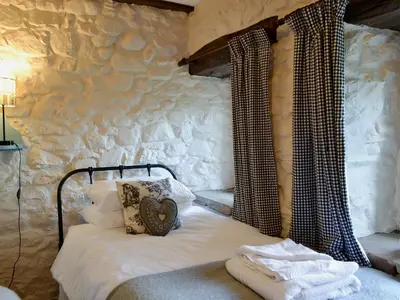 a bedroom with a bed and a stone wall at Branthwaite Stable in Caldbeck