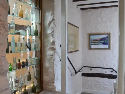 a room with a shelf filled with glass bottles at Branthwaite Stable in Caldbeck