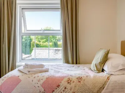 a bedroom with a bed and a large window at Jame's Cottage in Keswick