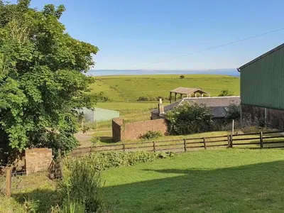 a view of a farm with a fence and a field at Dairy Cottage in Girvan