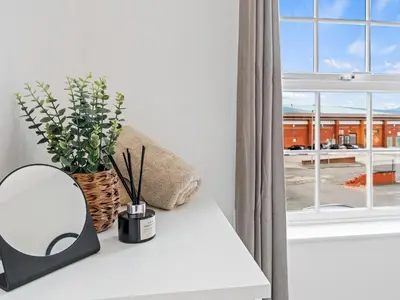 a mirror and flowers on a table next to a window at Modern 2-Bedroom Apartment with Free Parking in Warrington in Moffat