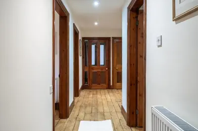 a hallway with wooden doors and a tile floor at Wreay Lodge - Fellside Home with Lake Views in Watermillock