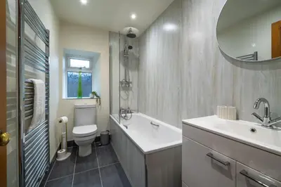 a bathroom with a sink and a toilet and a mirror at Wreay Lodge - Fellside Home with Lake Views in Watermillock