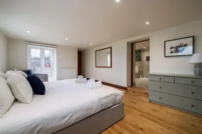 a bedroom with a large white bed and a dresser at Wreay Lodge - Fellside Home with Lake Views in Watermillock