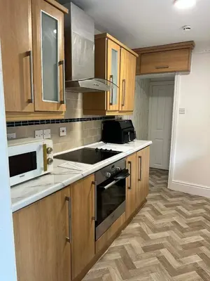a kitchen with wooden cabinets and a stove top oven at Comfortable Stay with Free Parking in Cleator