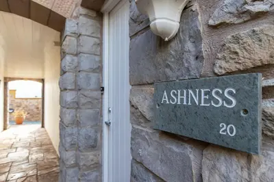 a sign on the side of a stone wall with a sign for a entrance at Underscar - Ashness in Applethwaite