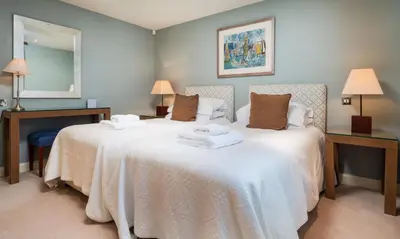 two beds in a room with two lamps and a mirror at Brackenburn in Applethwaite