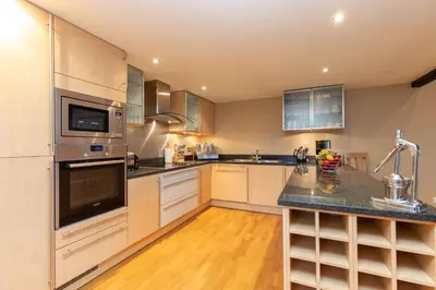 a kitchen with stainless steel appliances and wooden floors at Castlerigg in Applethwaite