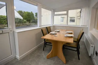 a dining room with a wooden table and windows at The Croft in Ramsey