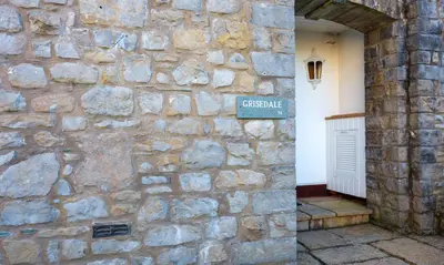 a stone wall with a street sign on it at Grisedale in Applethwaite
