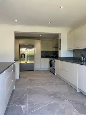 a large kitchen with white cabinets and stainless steel appliances at Fairway House- Stylish refurbished property in Moffat