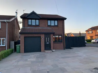 a brick house with a garage in a driveway at Fairway House- Stylish refurbished property in Moffat