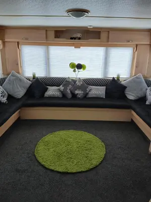 a living room with a couch and a green rug at Mags Home from Home at Southerness in Mainsriddle