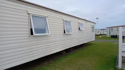 a side view of a mobile home with three windows at Mags Home from Home at Southerness in Mainsriddle