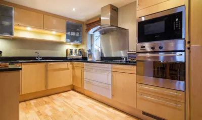 a kitchen with stainless steel appliances and wooden cabinets at Underscar - Newlands in Keswick