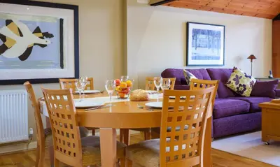 a dining room with a table and a purple couch at Underscar - Seatoller in Keswick